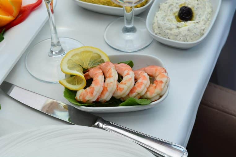 Assiette de crevettes apéritives dressées sur un plateau, avec sauce et garnitures pour un apéro gourmand entre amis.
