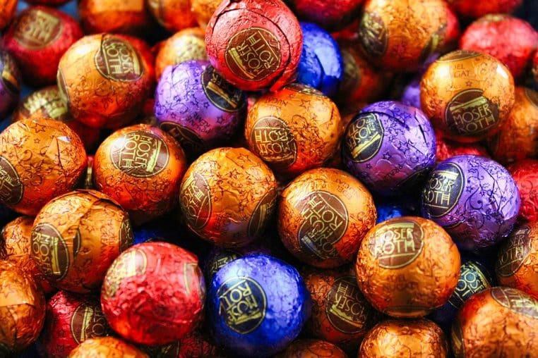 Ensemble de petites boules de chocolat de Noël multicolores, posées sur une table, rappelant les assortiments festifs pour décorer la maison.