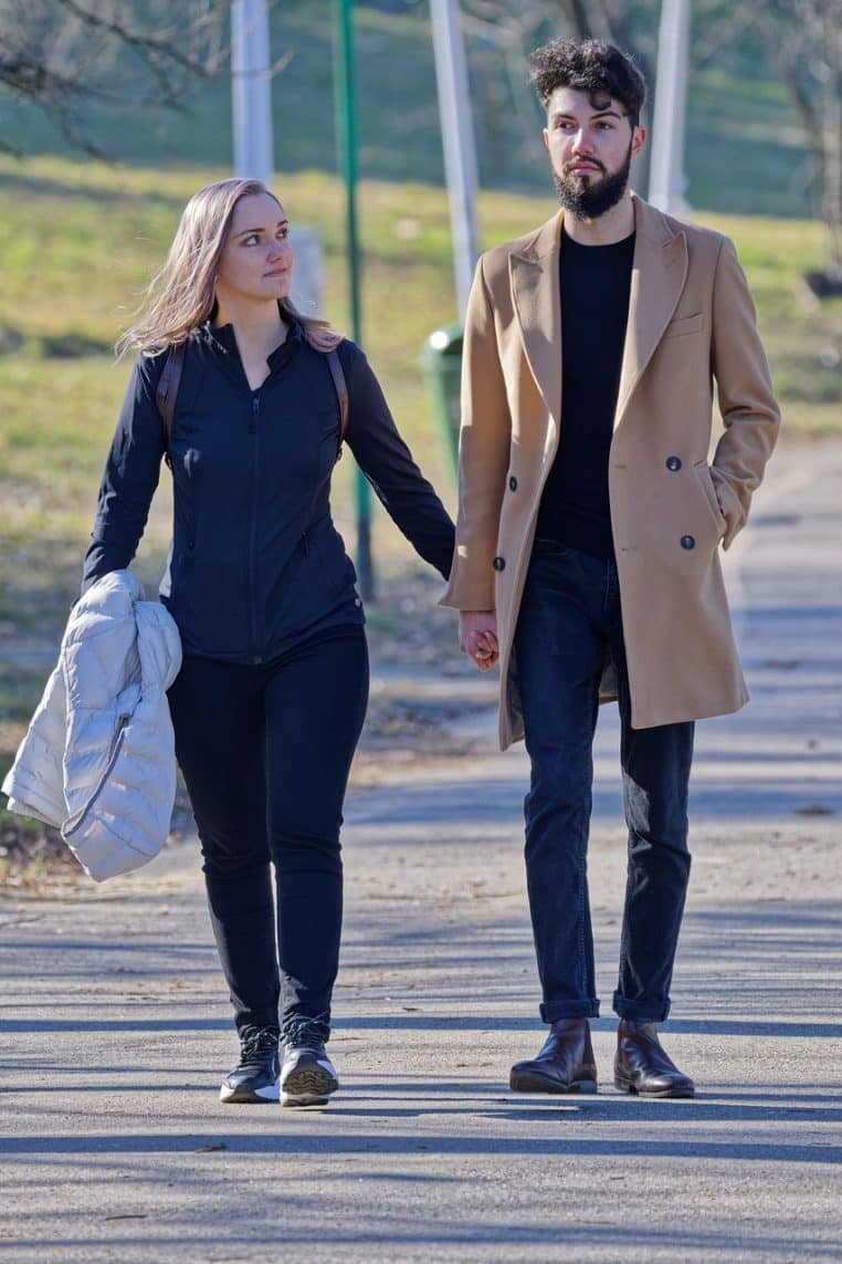 un couple de dos, en promenade sur une allée de parc, évoquant une retraite paisible mais potentiellement fragilisée par un gel de pension.