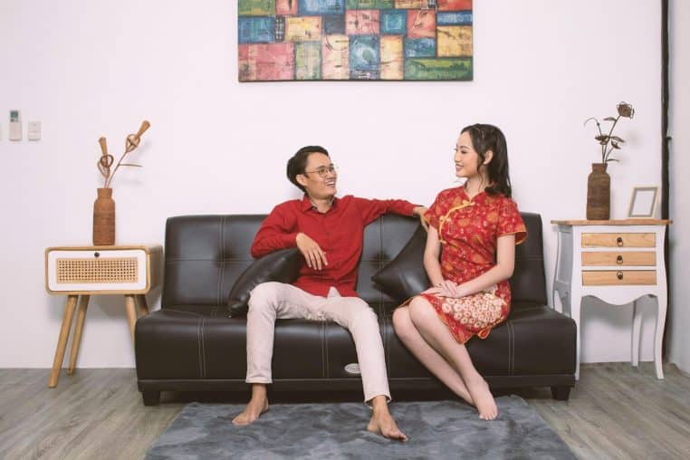 Un couple assis sur un grand canapé dans un salon lumineux, chacun tourné vers son activité dans un décor moderne.