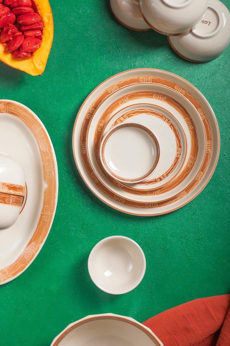 Vue de dessus d’un ensemble d’assiettes posées à plat sur une surface, dont plusieurs modèles verts utilisés pour un dressage soigné.