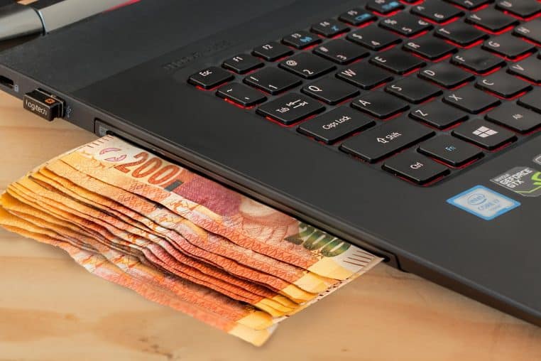 Billets posés près d’un clavier d’ordinateur, symbolisant les paiements en ligne et les opérations bancaires sur Internet