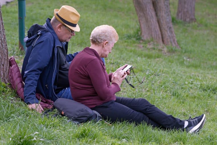 Couple de retraités marchant enlacés dans un parc arboré, symbole des seniors qui dépendent de leur pension pour maintenir un niveau de vie correct.