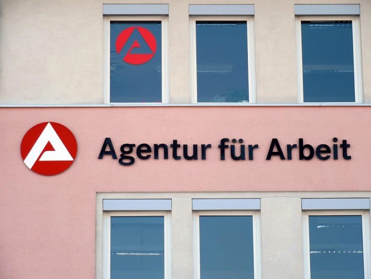 Façade d’une agence pour l’emploi, avec logo rouge et inscription « Agentur für Arbeit » au-dessus de plusieurs fenêtres.