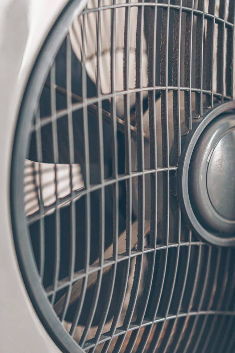 Ventilateur domestique en gros plan, posé dans une pièce lumineuse, évoquant les appareils saisonniers souvent oubliés sur la prise.