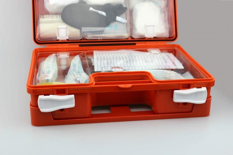 Valise de premiers secours orange ouverte, remplie de matériel médical, posée sur une surface claire, prête à être emportée en cas de crise.