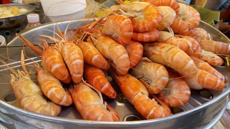 Crevettes roses disposées sur de la glace pilée, prêtes à être cuisinées pour un plat riche en protéines et léger en calories.