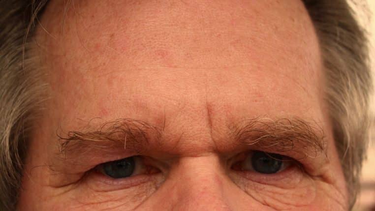 Gros plan horizontal sur le haut du visage d’un homme aux sourcils froncés, montrant des rides et un regard tendu qui évoquent la fatigue et la concentration visuelle.