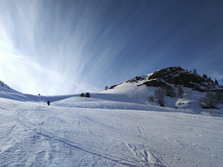 Vue sur une station de ski française avec pistes enneigées, remontées mécaniques et montagnes couvertes de neige abondante.