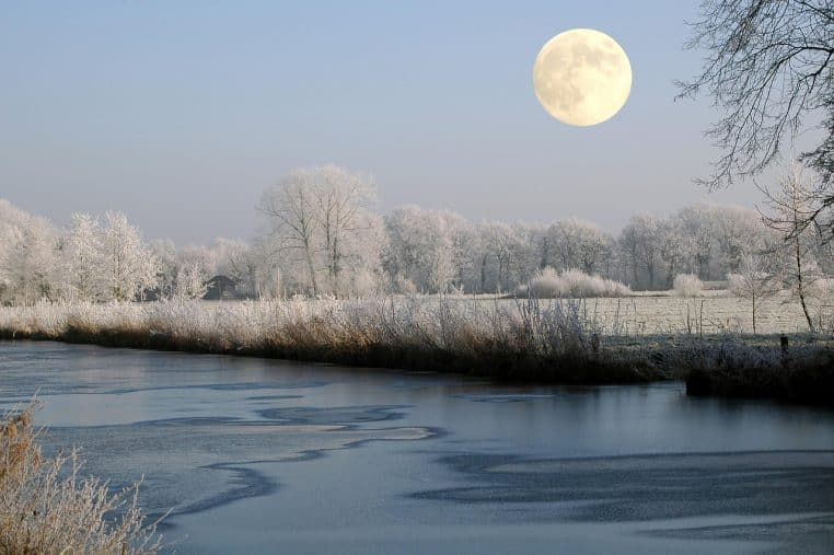 Pleine lune brillante se reflétant sur un bras de mer en hiver, ciel dégagé et paysage froid baignés de lumière blanche