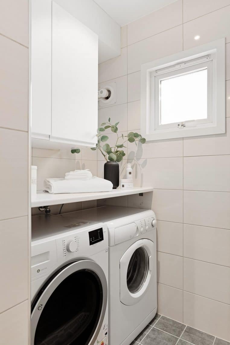 Intérieur de buanderie moderne avec machine à laver et rangements, illustrant l’importance d’un espace bien organisé pour prendre soin de son linge au quotidien.