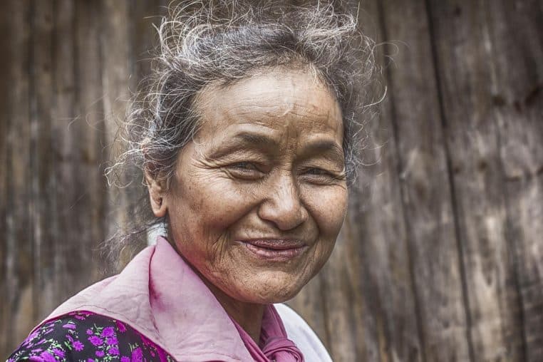 Un couple enlacé assis dans un salon fleuri, souriant l’un vers l’autre dans un intérieur cosy et coloré.
