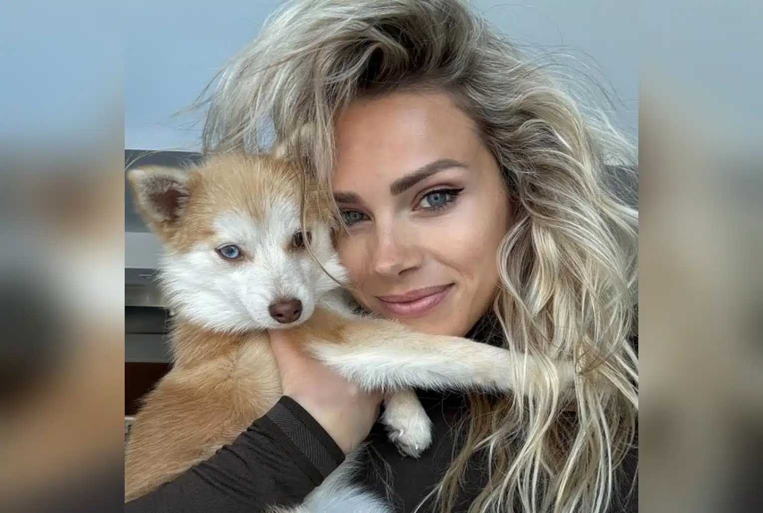 Marion Rousse prend un selfie avec son chiot Pomsky roux et blanc, qu’elle tient dans ses bras, au premier plan sur fond flou.