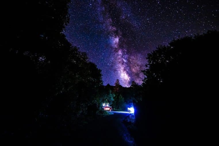 Voie lactée brillante au-dessus d’un campement illuminé, rappelant le lien entre observation du ciel nocturne et compréhension du cosmos