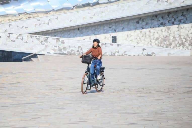 Femme en vélotaf sur un vélo électrique à Paris, casque pliable sur la tête, symbolisant un usage du VAE conforme aux règles et à la sécurité quotidienne.
