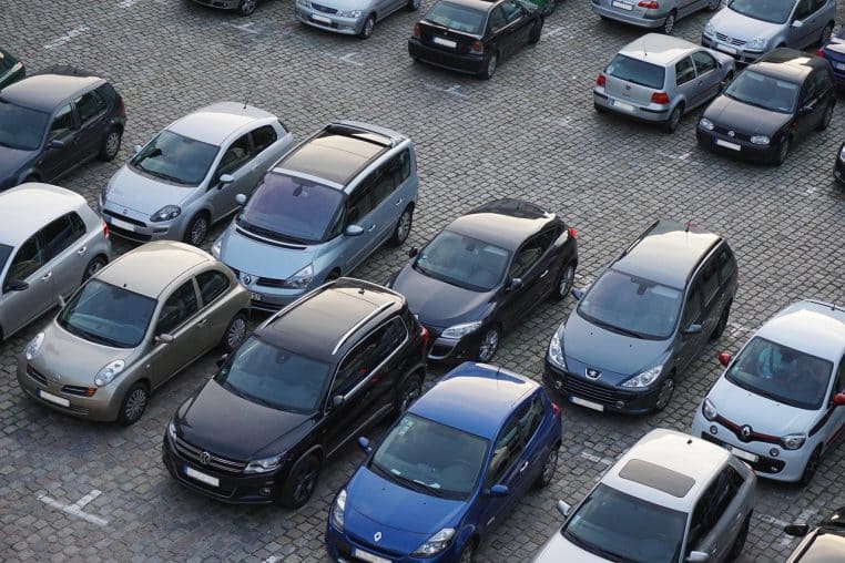 : Vue aérienne d’un grand parking rempli de voitures alignées, évoquant la question de la raréfaction des places en zone urbaine.