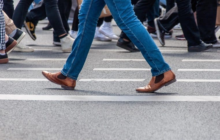 Piétons traversant un passage protégé dans une grande ville, avec véhicules à l’arrêt, mettant en avant la circulation en milieu urbain.