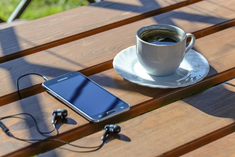 Tasse de café et smartphone posé sur une table en bois, symbolisant un moment de détente tout en consultant son forfait mobile.
