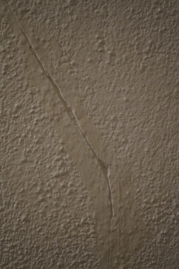 enduit sur une fissure pour lisser un plafond avant peinture, gros plan sur le couteau et la matière.
