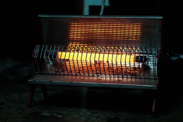 Radiateur d’appoint lumineux diffusant une lumière jaune chaude, posé dans une pièce sombre pour réchauffer l’atmosphère.