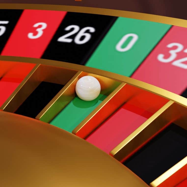 Détail d’une roue de roulette de casino avec la bille posée sur une case verte, évoquant les dépenses de jeu d’argent