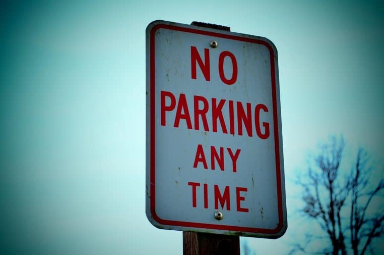 Gros plan sur un panneau « No parking any time » rouge et blanc, rappelant l’interdiction totale de stationnement à proximité.