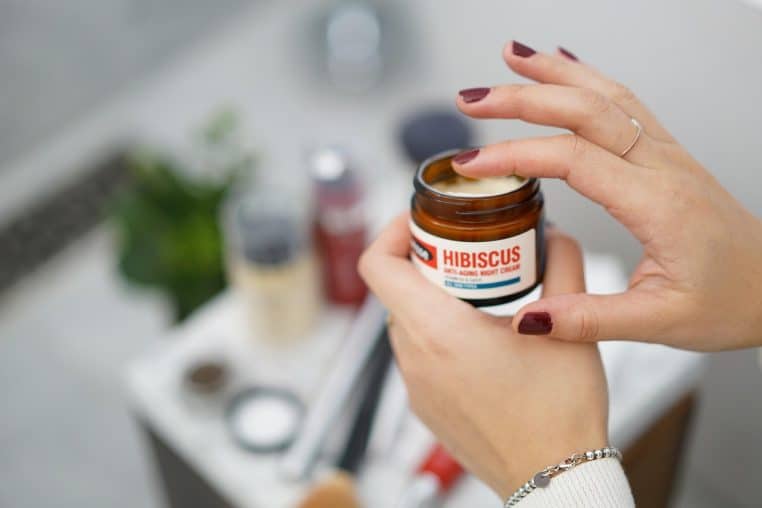 Salle de bain lumineuse avec serviettes et produits de soin alignés, au centre un flacon de crème dédié à la routine nocturne.