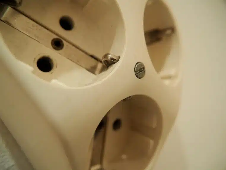 Plusieurs prises électriques murales et fiches branchées sur un mur blanc rappellent l’impact des appareils laissés connectés en permanence au réseau.