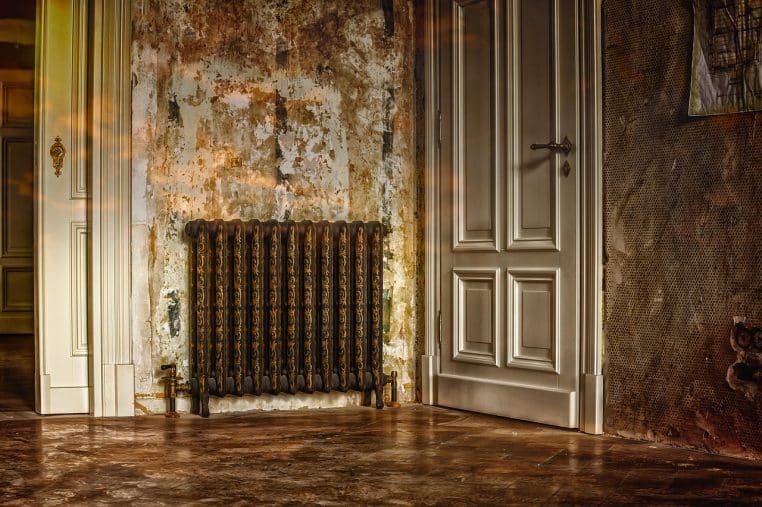 Radiateur moderne sous une fenêtre d’appartement avec vue extérieure hivernale, illustrant les pertes de chaleur possibles dans les pièces mal isolées.