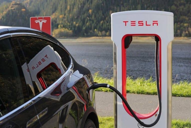 Tesla en charge sur une borne rapide au bord d’un lac, montrant l’utilisation quotidienne d’une voiture électrique à batterie