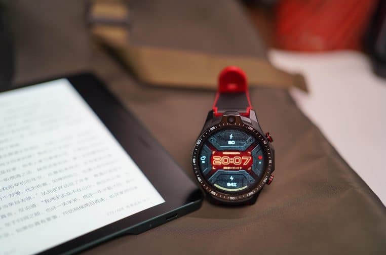 Poignet portant une montre connectée à écran digital lumineux, main posée sur un bureau, ambiance de travail moderne et technologique