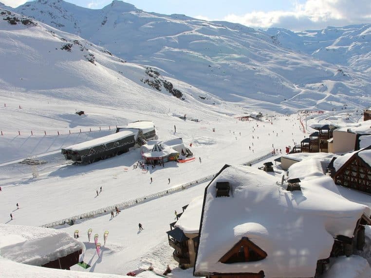 Vue hivernale de Val Thorens avec les immeubles de la station au pied des pistes enneigées et des skieurs en pleine descente