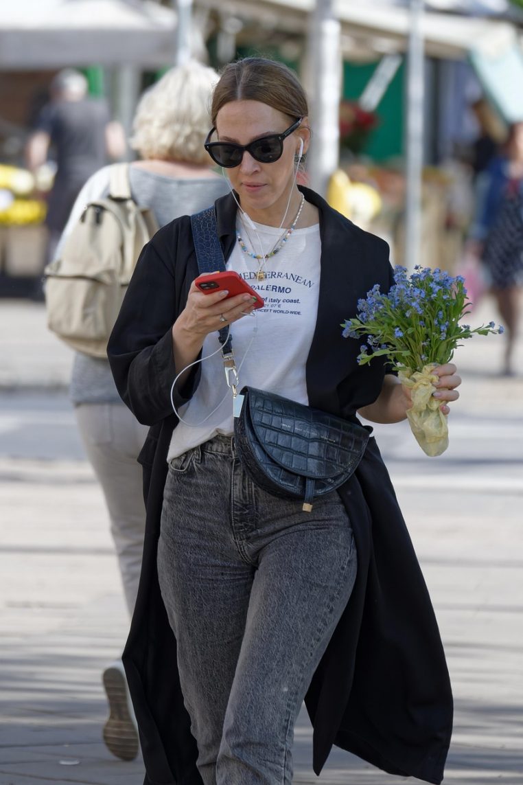 Jeune femme marchant dans une rue urbaine, smartphone à la main, profitant de son forfait 4G pour rester connectée en déplacement.