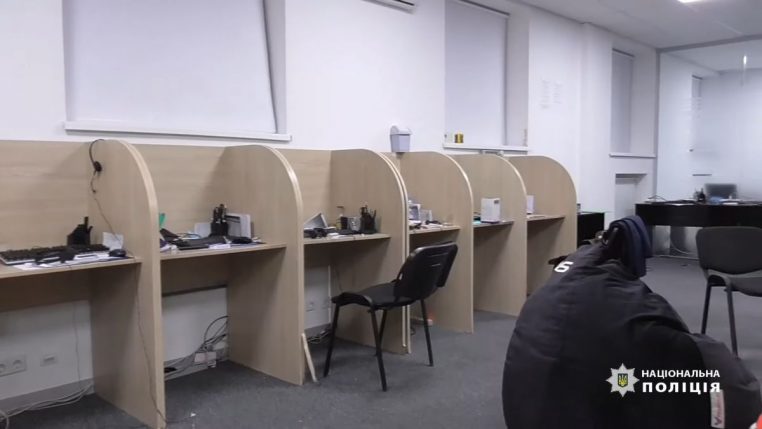 Vue d’un call center frauduleux démantelé par la police, avec plusieurs postes informatiques alignés, illustrant la lutte contre les escroqueries téléphoniques.