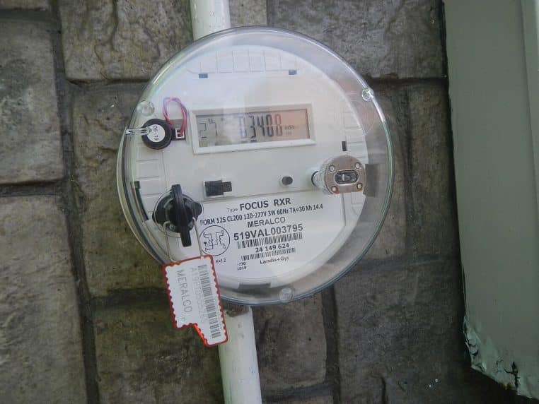 Série de compteurs électriques installés sur un bâtiment, avec affichage à cristaux liquides aligné en façade dans une rue urbaine.