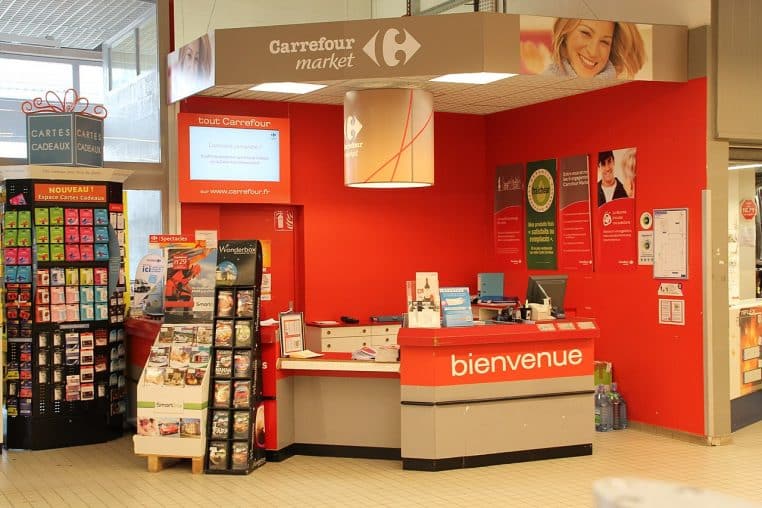 Espace caisse et accueil d’un supermarché en France, comptoir central et signalétique au-dessus des lignes.