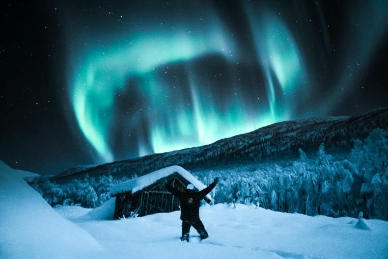 Vibrant northern lights illuminate a winter night sky in snowy Norway. Perfect for travel and nature enthusiasts.