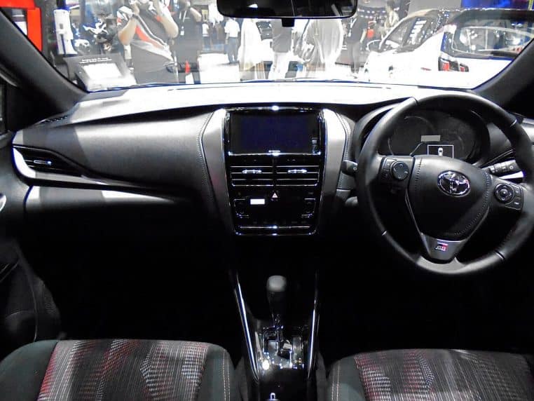 Intérieur Toyota Yaris avec volant multifonction, écran central, console noire et ambiance cockpit orientée conducteur.
