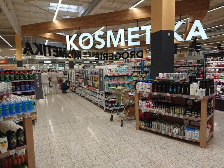 Allée de magasin dédiée aux cosmétiques, étagères remplies de produits, scène typique d’achat en parfumerie.