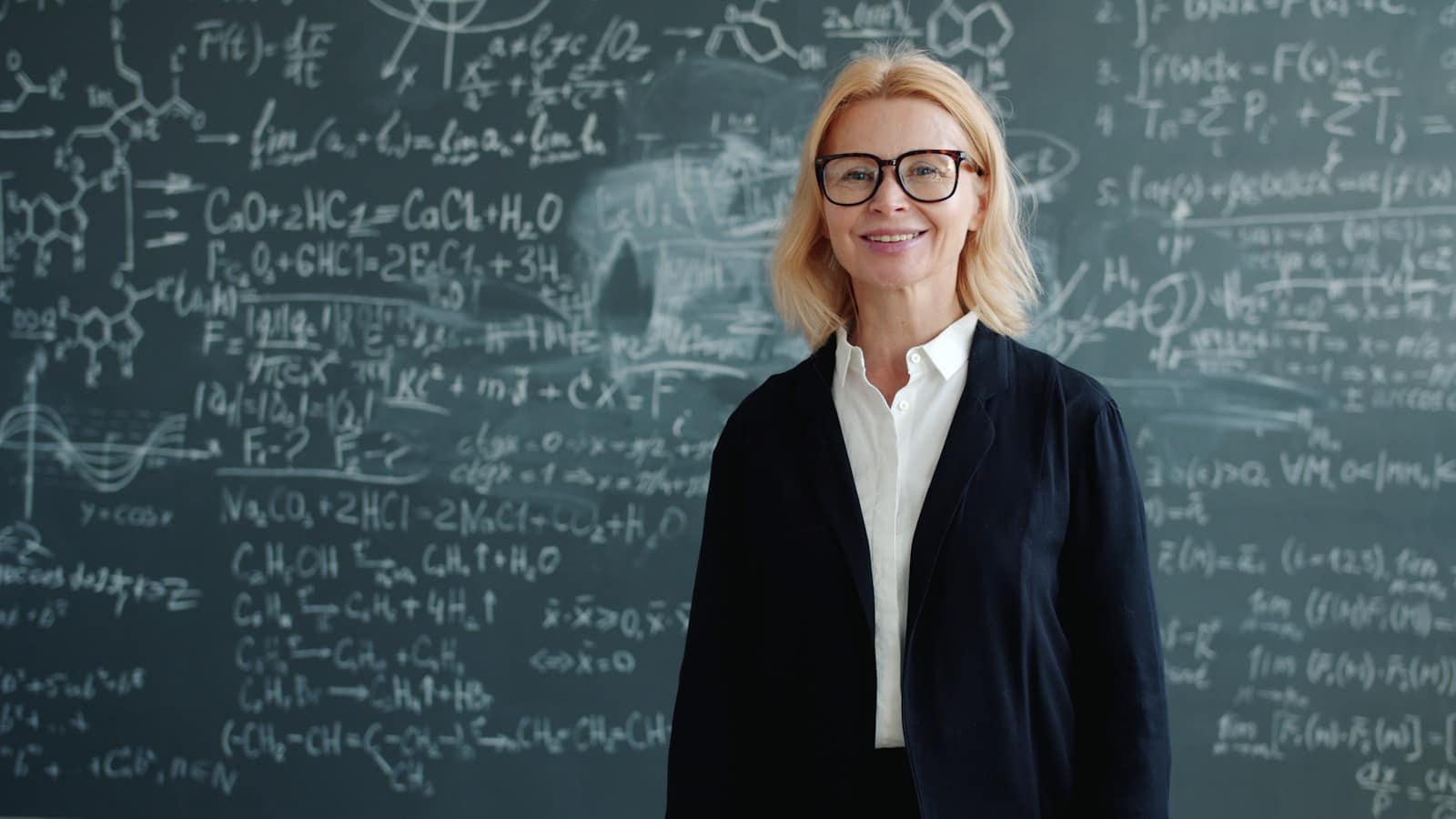Woman smiling in front of blackboard with math equations