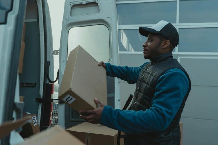 Delivery man unloading parcels from van for shipment.