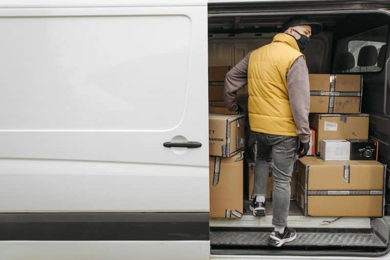 A deliveryman unloading packages from a van, showcasing modern logistics.
