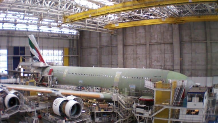 Hall d’assemblage Airbus à Toulouse avec un gros-porteur en cours d’équipement, vu de l’intérieur, au milieu des plateformes et des ponts roulants.