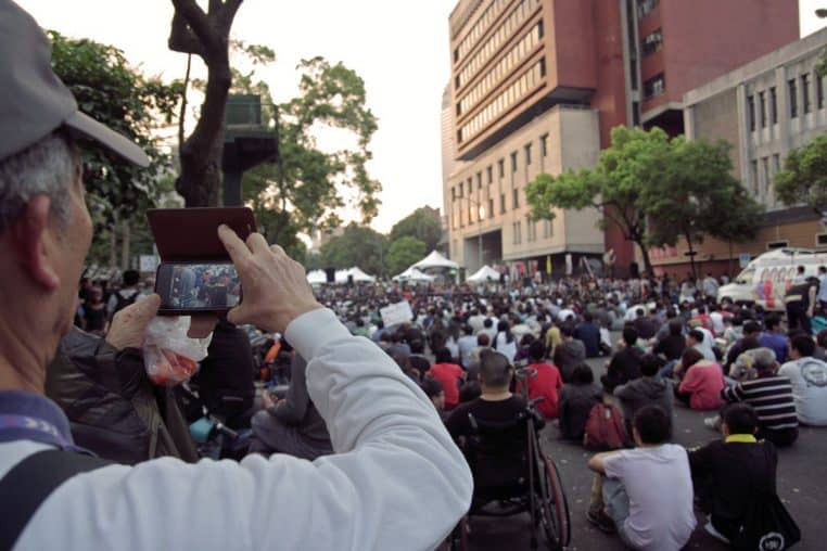 Paiement sans contact : une main approche un smartphone d’un terminal de carte bancaire près d’une tasse de café.