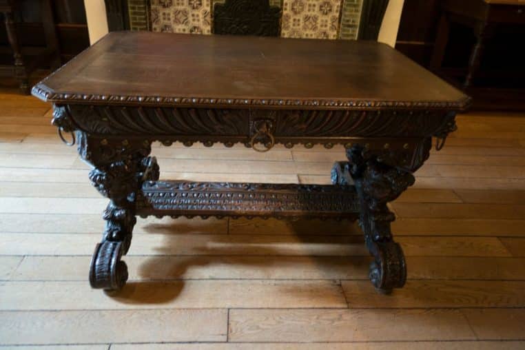 Table ovale ancienne en bois verni, vue trois-quarts, style classique, posée en intérieur sur sol clair.