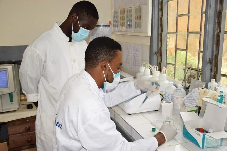 Technicienne en laboratoire manipulant des échantillons, gants et blouse, illustration d’analyses de produits.