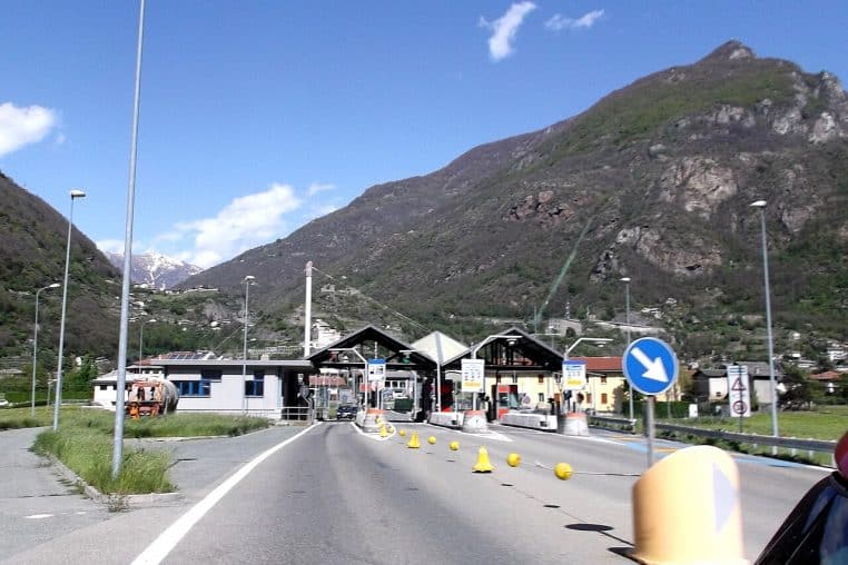 Poste de péage sur l’autoroute A5 en vallée d’Aoste, en Italie, avec cabines et relief alpin.