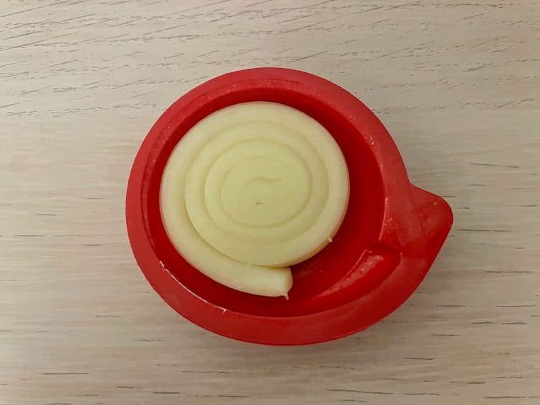 Gros plan d’un Mini Babybel avec sa coque rouge intacte, posé sur une table, prêt à être ouvert