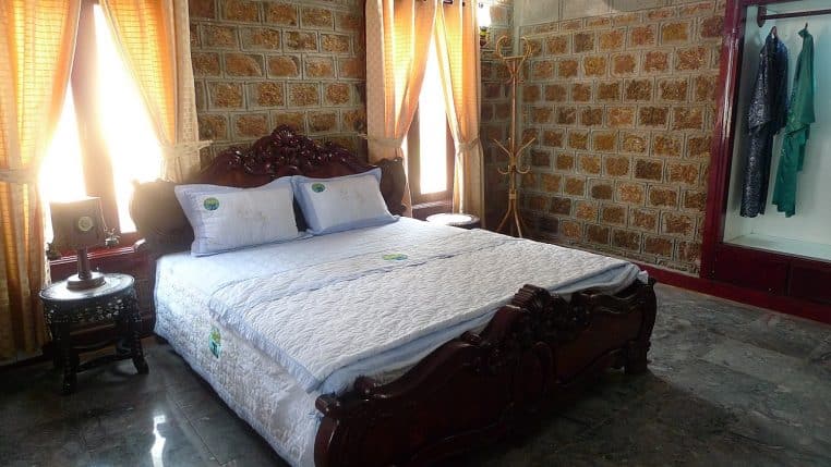 Chambre avec lit en bois et linge de lit clair, entourée de meubles assortis et d’une décoration chaleureuse en bois.