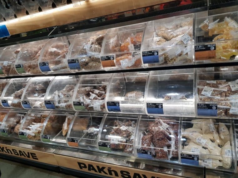 Rayon de vrac en supermarché avec bacs transparents remplis de fruits secs, céréales et graines
